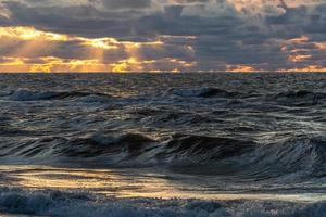 costa del mar báltico con guijarros y hielo al atardecer foto