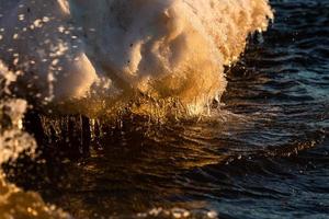 costa del mar báltico con guijarros y hielo al atardecer foto