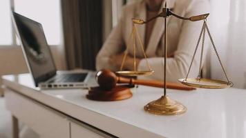 Business and lawyers discussing contract papers with brass scale on desk in office. Law, legal services, advice, justice and law concept picture with film grain effect video