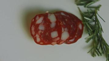 charcutaria plana com salame, diferentes tipos de queijo. tem frutas secas, nozes diversas e mel. arranjo de férias com velas acesas video