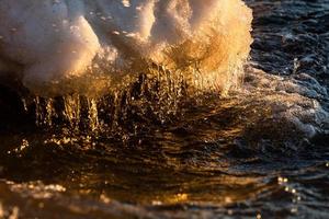 costa del mar báltico con guijarros y hielo al atardecer foto