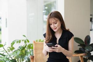 Asian working woman hold mobile phone text message, chat conversation or using social media. Businesswoman use smartphone browse web, read e-book, trade stocks. Communication technology concept. photo