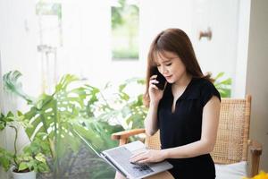 Freelance business woman calling on mobile smartphone while working with laptop, businesswoman mobile phone to calling with customers or shopping online. Smart phone conversation conferrence. photo