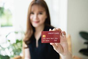 Woman holding showing credit card to shopping online. asian woman working at home. Online shopping, e-commerce, internet banking, spending money, working from home concept. photo