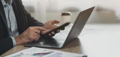 Crop picture. business man using smartphone working with laptop on table, mobile phone to search or social media or shopping online or stock or crypto currency. Smart phone conversation conferrence. photo