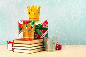 tres coronas de los tres reyes magos con libros, cajas de regalo de navidad y copos de nieve foto