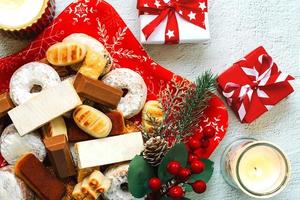 Top view of Nougat christmas sweet,mantecados and polvorones with christmas ornaments on a christmas star shaped red plate. Assortment of christmas sweets typical in Spain photo