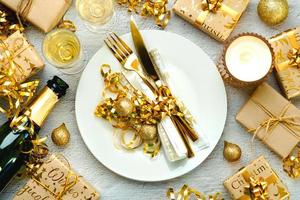 Christmas dinner concept. Top view of golden cutlery on a plate with christmas ornament and champagne bottle. Christmas concept background photo