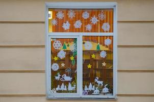 la ventana está decorada con copos de nieve, ciervos tallados en papel. Decoración navideña foto