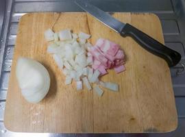 The sliced onion with the sliced ham on the chopping board. photo