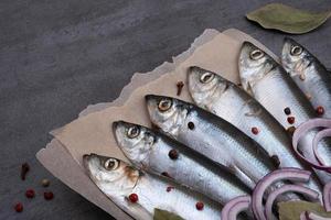 Several pickled herrings with spices on parchment paper photo