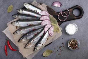 Several pickled herrings with spices on parchment paper photo