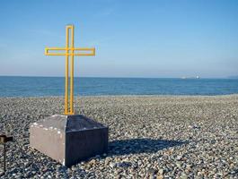 cruz en la orilla de guijarros. monumento en la playa. foto