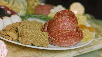 Flat charcuterie with salami, different kinds of cheese. It has dried fruits, various nuts and honey. Holiday arrangement with burning candles video