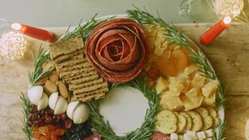 plato de charcutería con salami, diferentes tipos de queso. tiene frutos secos, frutos secos varios y miel. arreglo de vacaciones con velas encendidas video