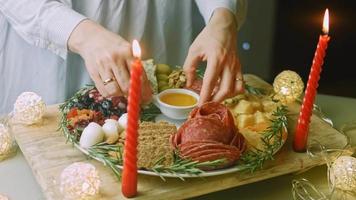 Flat charcuterie with salami, different kinds of cheese. It has dried fruits, various nuts and honey. Holiday arrangement with burning candles video