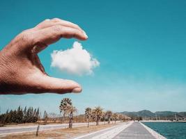 Close-up view of a hand try to grab a single cloud photo