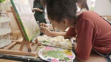une fille noire se concentre sur la peinture acrylique couleur sur toile avec un enseignant et des enfants dans une classe d'art, l'apprentissage créatif avec des talents et des compétences dans l'enseignement en studio de l'école primaire. video