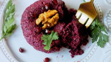 de meisje smaakt pkhali. pkhali traditioneel Georgisch voedsel. rode biet is gebruikt voor de Purper kleur. okkernoot is gebruikt voor decoratie video