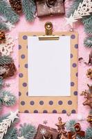 Blank paper on tablet with frame made frome pine tree branches and Christmas decoration in snow top view photo