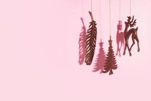 árbol de año nuevo de navidad, ciervos y juguetes de brillo de plumas sobre fondo rosa con espacio de copia foto