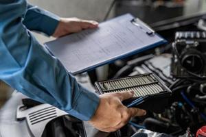 técnico sostenga y verifique el filtro de aire del motor en la sala del motor y verifique el trabajo de servicio de lista en el garaje, concepto de servicio de camión foto