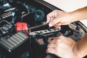 un hombre sostiene y abre la tapa de la batería adicional para agregar destilado, mantenimiento e inspecciones para prolongar la vida útil de la batería del automóvil foto