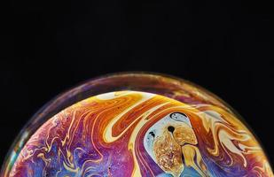 Virtual reality space with abstract multicolor psychedelic planet. Closeup Soap bubble like an alien planet on black background photo