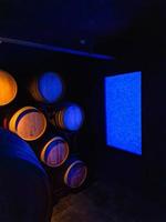 Old cellar with illuminated stacked oak barrels and bottles in a winery photo