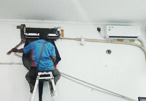 West Java, Indonesia in July 2022. A technician is repairing and cleaning a broken home Air Conditioner. photo