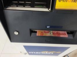 Jakarta, Indonesia in July 2022. Several hundred thousand rupiah bills came out of the Automated Teller Machine or ATM from Bank Mandiri. photo