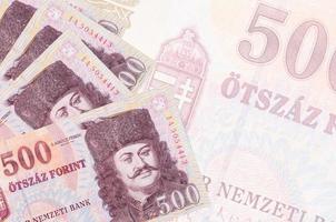 500 billetes de florín húngaro se encuentran apilados sobre el fondo de un gran billete semitransparente. fondo de negocios abstracto foto