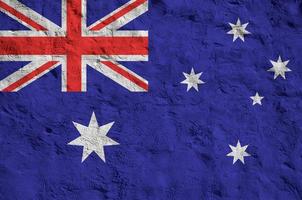 Australia flag depicted in bright paint colors on old relief plastering wall. Textured banner on rough background photo