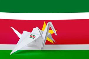 Suriname flag depicted on paper origami crane wing. Handmade arts concept photo