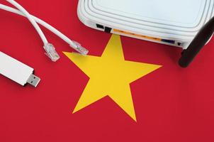 Vietnam flag depicted on table with internet rj45 cable, wireless usb wifi adapter and router. Internet connection concept photo