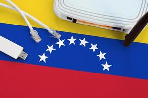 Venezuela flag depicted on table with internet rj45 cable, wireless usb wifi adapter and router. Internet connection concept photo