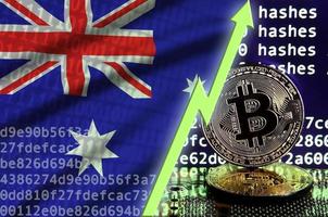 bandera de australia y flecha verde ascendente en la pantalla de minería de bitcoin y dos bitcoins dorados físicos foto