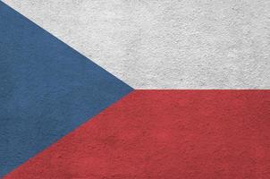 Czech flag depicted in bright paint colors on old relief plastering wall. Textured banner on rough background photo