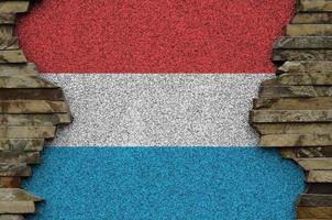Luxembourg flag depicted in paint colors on old stone wall closeup. Textured banner on rock wall background photo