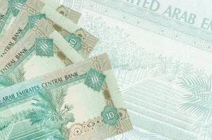 Los billetes de 10 dirhams de los emiratos árabes unidos se encuentran apilados en el fondo de un gran billete semitransparente. fondo de negocios abstracto foto