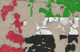 United Arab Emirates flag depicted in paint colors on old obsolete messy concrete wall closeup. Textured banner on rough background photo