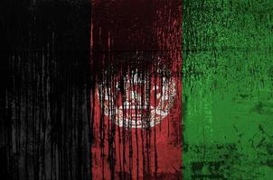 Afghanistan flag depicted in paint colors on old and dirty oil barrel wall closeup. Textured banner on rough background photo