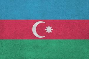 Azerbaijan flag depicted in bright paint colors on old relief plastering wall. Textured banner on rough background photo