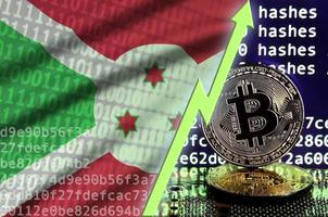 bandera de burundi y flecha verde ascendente en la pantalla de minería bitcoin y dos bitcoins dorados físicos foto