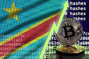 bandera de la república democrática del congo y flecha verde ascendente en la pantalla de minería bitcoin y dos bitcoins dorados físicos foto