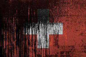 Switzerland flag depicted in paint colors on old and dirty oil barrel wall closeup. Textured banner on rough background photo