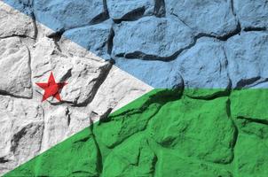 Djibouti flag depicted in paint colors on old stone wall closeup. Textured banner on rock wall background photo