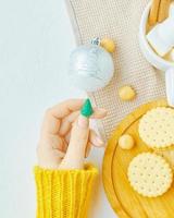 Women holds Christmas toy, cup of coffee, cookies and tablecloth on table. photo