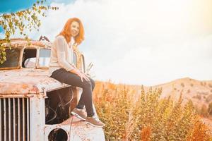 Woman sitting on rusty old classic truck. photo