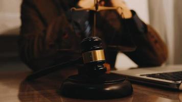 Justice and law concept.Male judge in a courtroom with the gavel, working with, computer and docking keyboard, eyeglasses, on table in morning light video